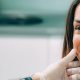 A dentist wearing gloves examines a smiling womans teeth in a dental clinic.